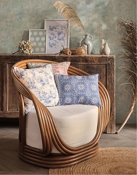 An armchair topped with three patterned cushions.