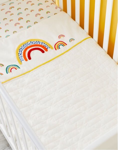 A toddler bed with rainbow pattern bedding.
