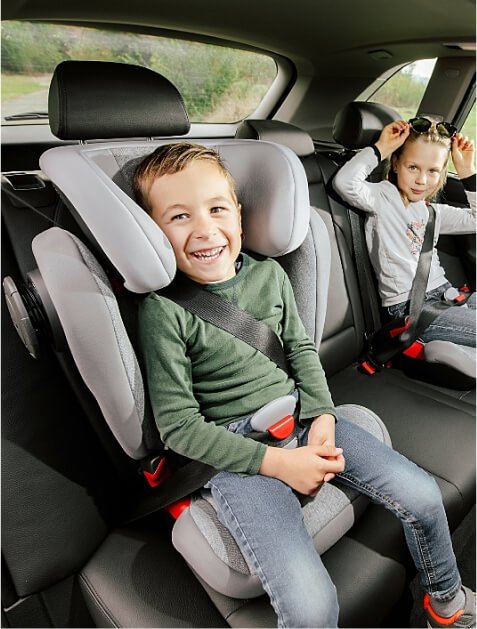 Two children in a car, one using a child seat