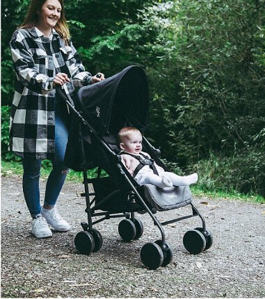 A woman walking in a park with a baby in a pushchair