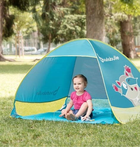 A baby sitting in a blue Badabulle Anti-UV Tent