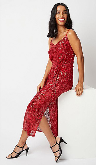 Woman sitting on a white box wearing a red sparkly dress