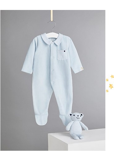 Billie Faiers blue velour sleepsuit on a hanger and plush teddy toy on a white plinth
