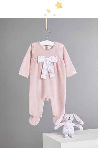 Billie Faiers velour floral bow sleepsuit on a hanger and plush teddy toy on a white plinth
