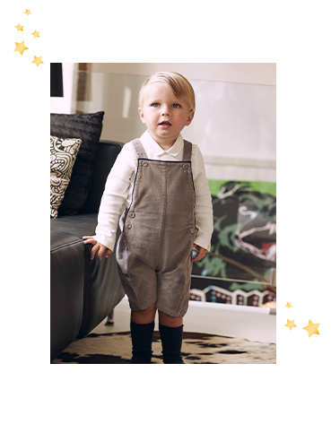 Child sitting down wearing a grey long sleeve top and striped navy and grey bottoms. 