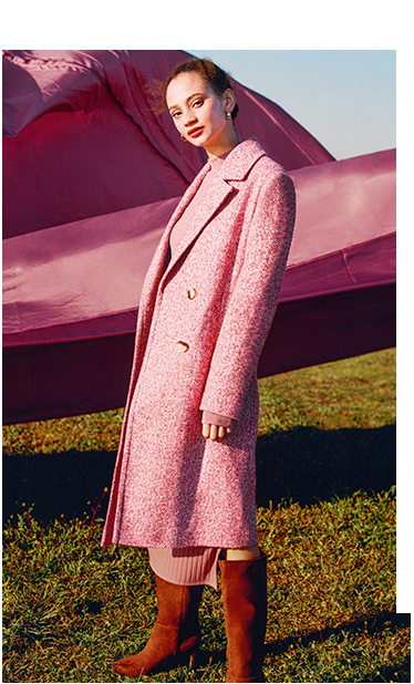 Side profile of woman wearing a long pink coat and brown boots