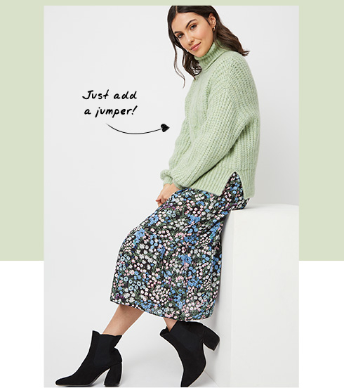 Woman wearing a floral dress with a green jumper over the top 