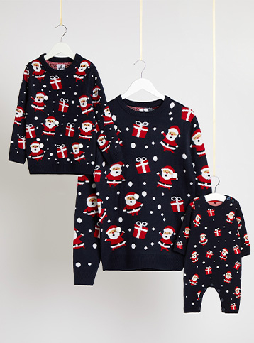 Matching adult and child navy Christmas jumpers and a baby all in one on hangers hanging from string