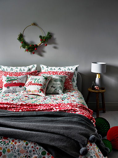 Floral Christmas bedding with cushions, a red throw and grey throw