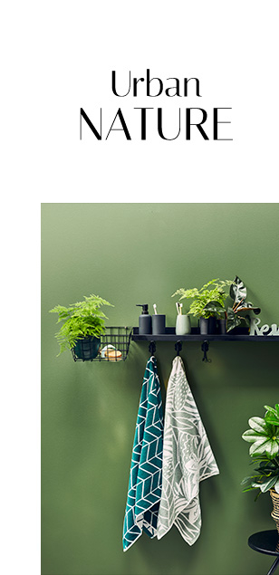 Shelf with bathroom accessories and plants and patterned towels hanging on hooks 