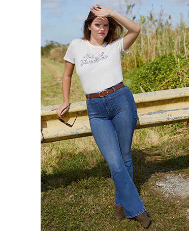 Woman in a field wearing a white slogan T-shirt and jeans
