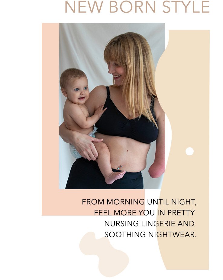 Woman with long blonde hair poses in black maternity bra holding baby girl wearing nappy in front of a white curtain.