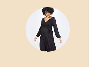 Woman with black curly hair poses wearing maternity black v-neck midi nursing dress.