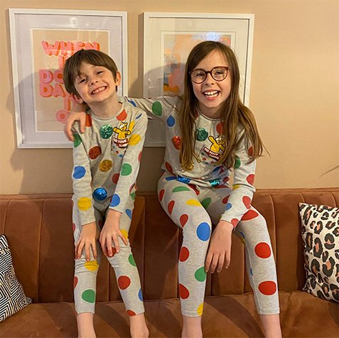 Boy and girl in matching Pudsey pyjamas in grey and multi coloured spots