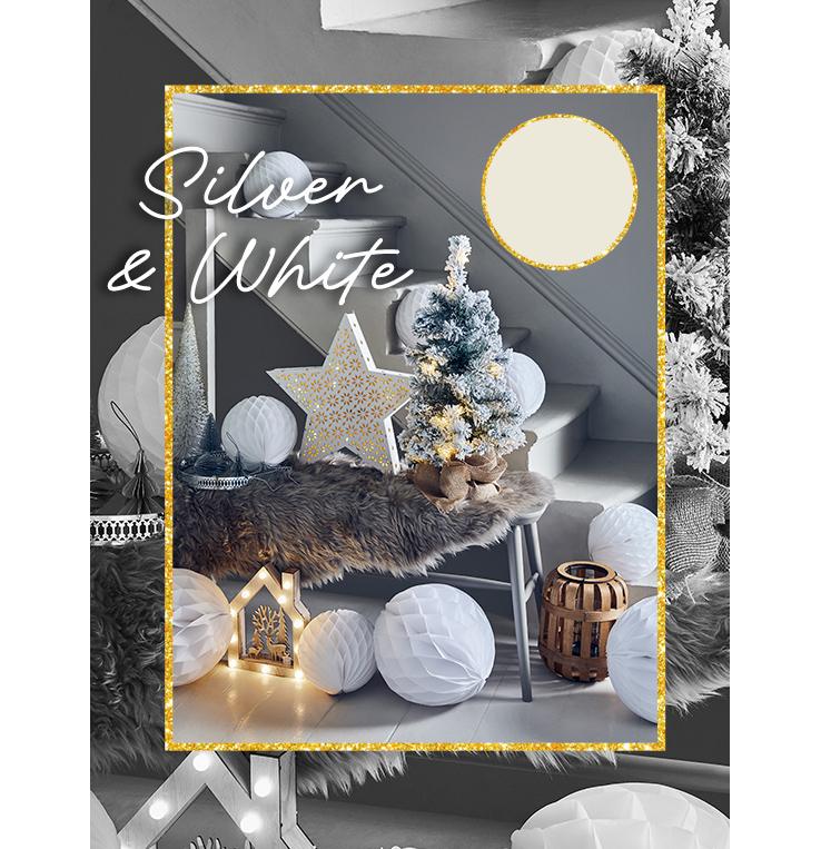 Grey table topped with a brown faux fur rug with white paper pom-pom decorations, light-up reindeer house, light-up white star and Christmas tree all in front of a white staircase.