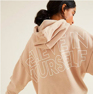Woman facing away wearing a beige 'Believe in yourself' slogan hoodie