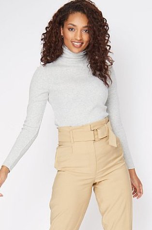 Woman wearing a grey turtle neck top with camel belted cropped trousers