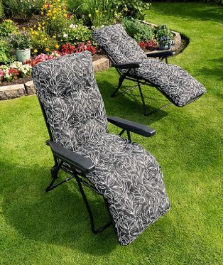 Two black leaf miami relaxer sunbeds in sunny garden with colourful plants and flowers in the background.