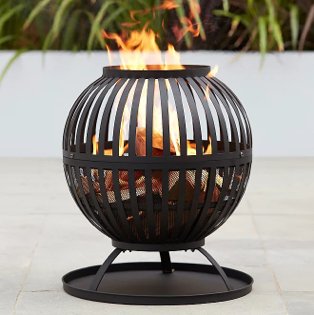 Black Expert Grill log burner lit on patio in garden.