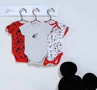 3 Disney Mickey Mouse bodysuits hanging from white hooks with black Mickey Mouse cushion below.