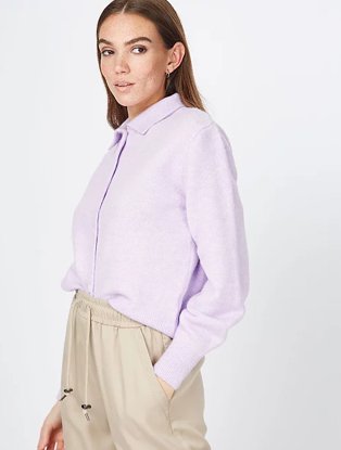 Woman poses side on wearing lilac collared long sleeve top and stone lounge trousers.