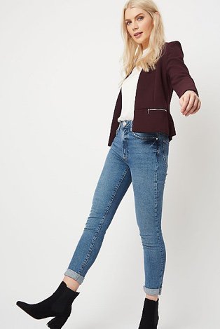 Woman in a purple formal textured zip detail blazer over a white jumper and jeans