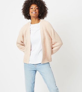 Woman in a pale pink ribbed waffle knit cardigan over a white top and light jeans