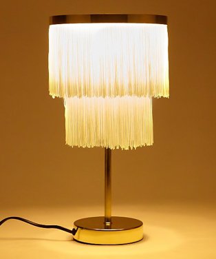 A lit up gold tone fringe table lamp