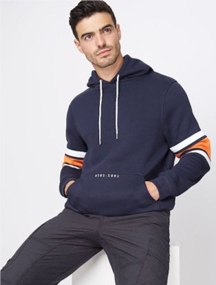 Man wearing black trousers with a navy stripe sleeve hoodie