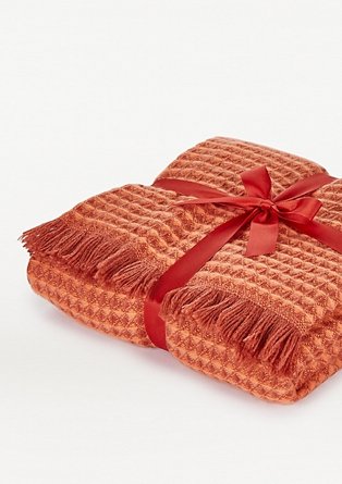 Orange waffle knit throw with tassel trims wrapped in satin bow.