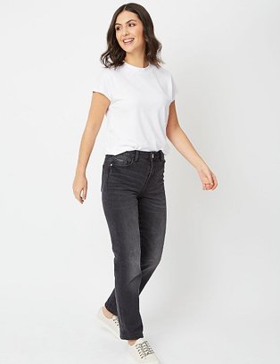 A woman wearing black wash denim high rise jeans with a white t-shirt and white trainers