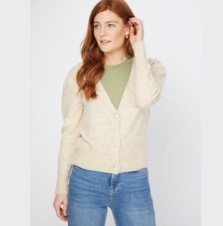 Red haired woman poses wearing khaki t-shirt and natural button-up cardigan over medium blue faded jeans.