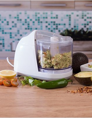 White food processor on wooden surface surrounded by ingredients.