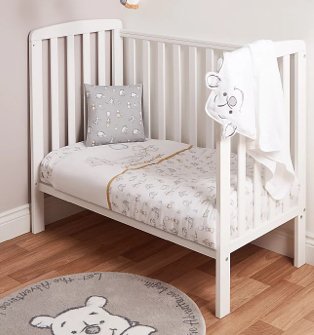 White Cot Bed with White and Yellow Disney Winnie the Pooh Duvet Set, Grey Disney Winnie the Pooh Cushion and Grey Disney Winnie the Pooh Rug.