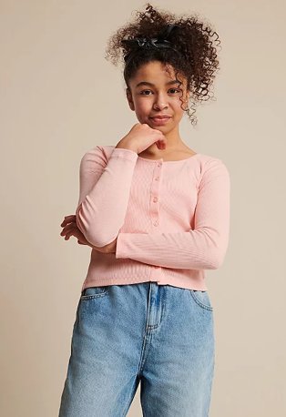 Girl poses wearing a pink button down cardigan and jeans.