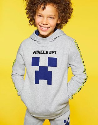 Child smiles wearing a grey Minecraft hoodie and joggers.