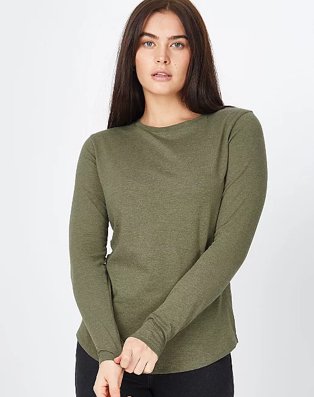 Woman poses wearing khaki long sleeved top and black jeans.
