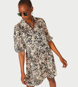 Woman poses wearing animal print balloon sleeve shirt dress and black circular sunglasses.