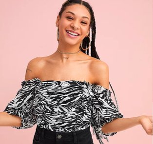 Woman poses smiling wearing monochrome zebra print ruched top tucked into black jeans.