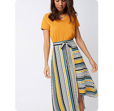 Woman wearing orange top with yellow stripe print asymmetric midi skirt