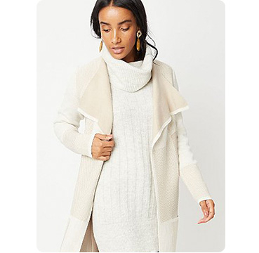 Woman wearing cream roll neck cable knit jumper and matching coat