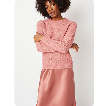 Woman wearing pink knitted jumper and satin look pink skirt