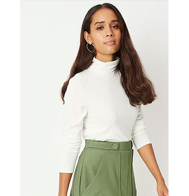 Woman wearing white roll neck jumper and green skirt