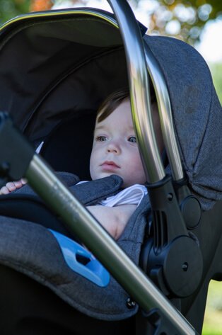 Baby lays in pushchair.