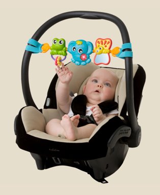 Baby lays in black and cream car seat playing with frog, elephant and butterfly mobile.