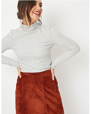 Woman wearing grey roll neck top and rust coloured skirt