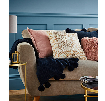 Blue pom pom throw and cushions on a sofa 