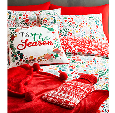 Red Christmas bedding with matching cushions, a red throw and a red hot water bottle