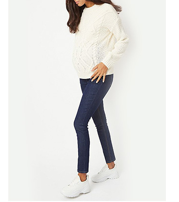 Pregnant woman wearing white jumper, jeans and white trainers