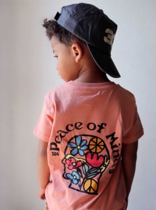 Child wearing printed t-shirt and a cap.